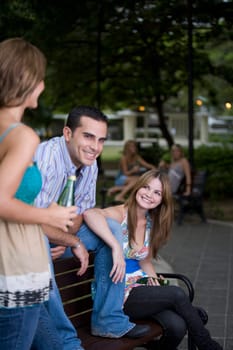 Young man sitting between two young women and smiling