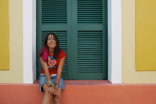 Portrait of a young woman sitting on a window sill and making a face
