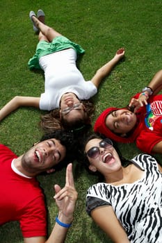High angle view of a young man lying on grass with three young women