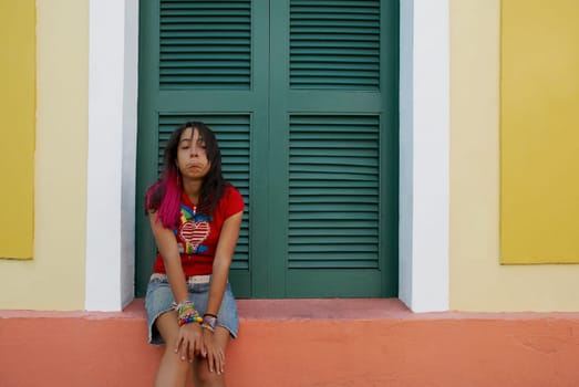 Young woman sitting on a window sill and making a face