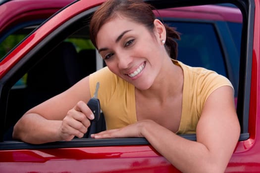 Portrait of a young woman sitting in a car and showing a car key