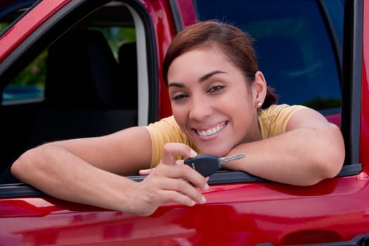 Portrait of a young woman leaning on the window of a car and showing a car key