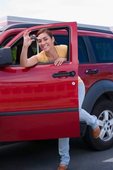 Portrait of a young woman showing a car key and smiling