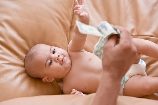 Close-up of a person's hand showing US paper currency to a baby boy lying on a couch
