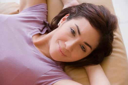 Portrait of a young woman lying on a couch and smiling