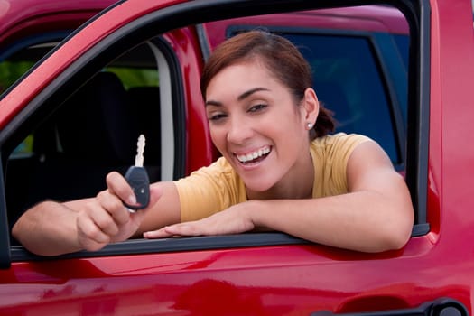 Portrait of a young woman leaning on the window of a car and showing a car key