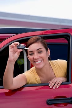 Portrait of a young woman showing a car key and smiling
