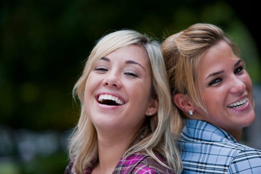 Portrait of two young women back to back and smiling