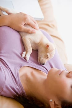 Young woman lying on a couch with a puppy lying on her