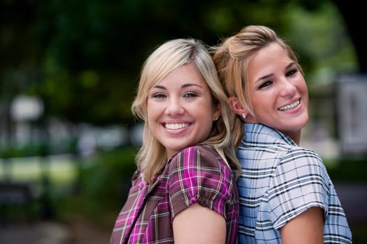 Portrait of two young women back to back and smiling