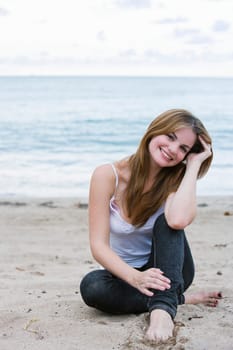Portrait of a young woman sitting on the beach and smiling