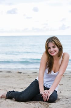 Portrait of a young woman sitting on the beach and smiling