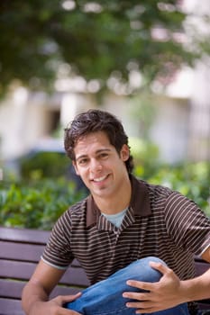 Portrait of a young man smiling with his hand on his knee