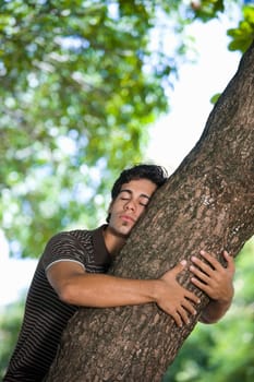Young man hugging a tree trunk