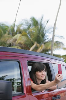 Young woman sitting in a car and taking a picture with a mobile phone
