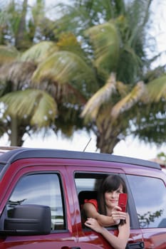 Young woman sitting in a car and taking a picture with a mobile phone