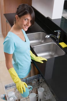 Teenage girl loading dishes into a dishwasher