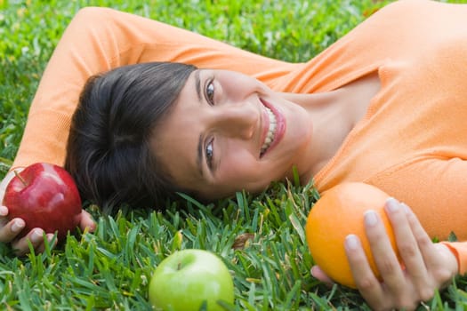 Teenage girl lying on grass and holding fruits