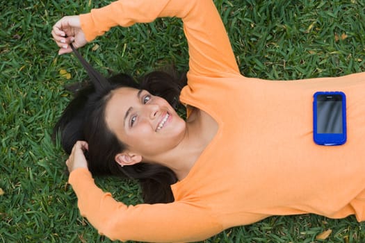 Teenage girl lying in a park with a mobile phone