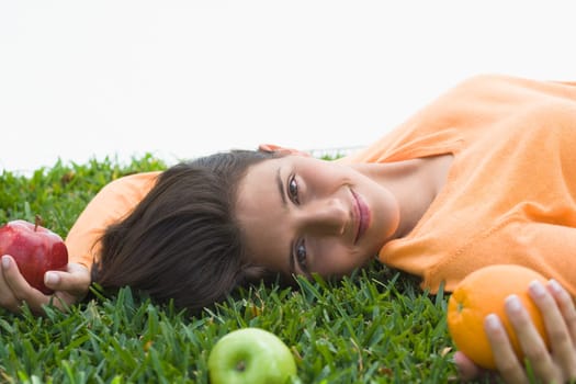 Teenage girl lying on grass and holding fruits