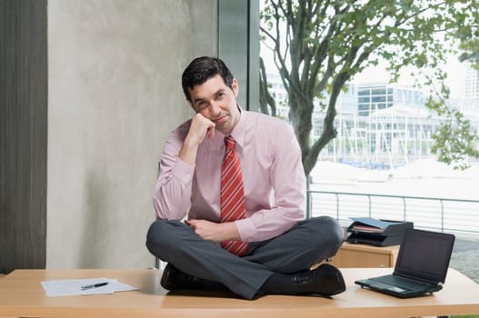 Portrait of a businessman sitting on a desk