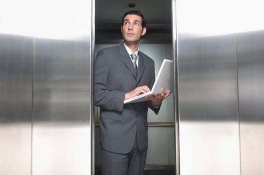 Businessman working on a laptop in an elevator