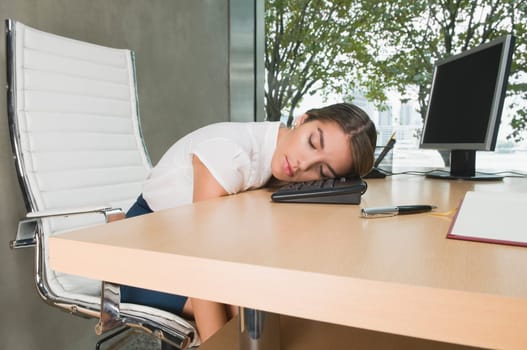 Businesswoman sleeping on a desk in an office