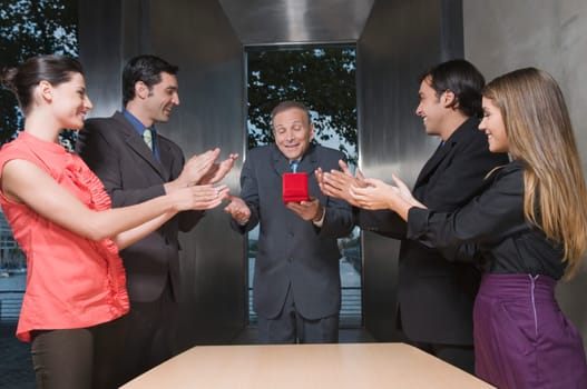 Business executives presenting a gift to their colleague in an office