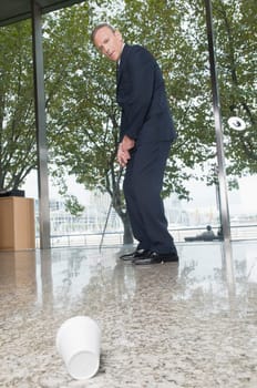 Businessman playing golf in an office