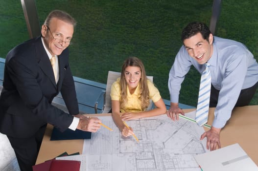 Portrait of business executives discussing a blueprint in an office