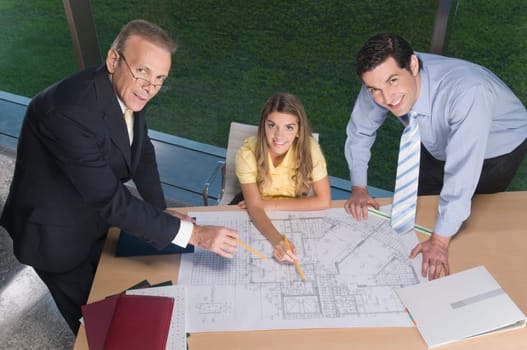 Portrait of business executives discussing a blueprint in an office
