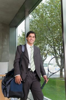 Businessman carrying a bag with a tennis racket