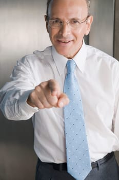 Businessman smiling and pointing forward in an office