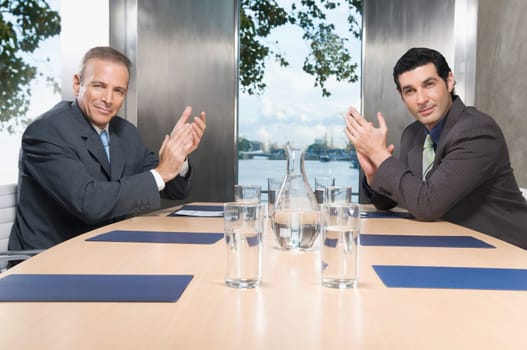 Two businessmen applauding in a conference room