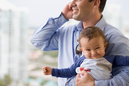 Man talking on a mobile phone and holding his son