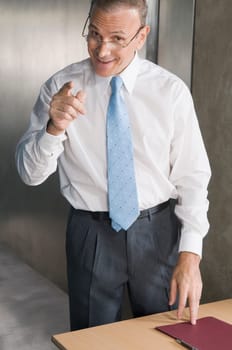 Businessman smiling and pointing forward in an office
