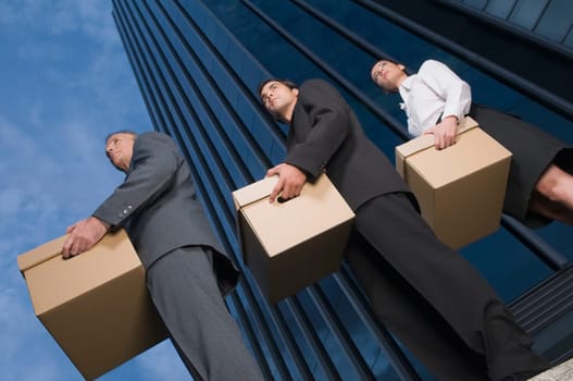 Low angle view of business executives carrying boxes