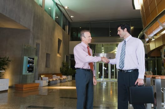Two businessmen shaking hands at an airport