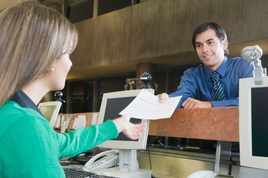 Man giving a document to female customer service representative