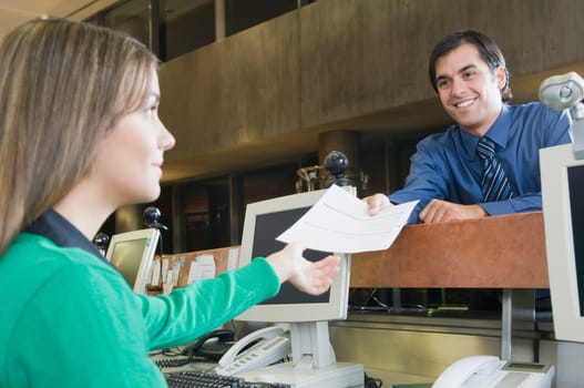 Man giving a document to female customer service representative