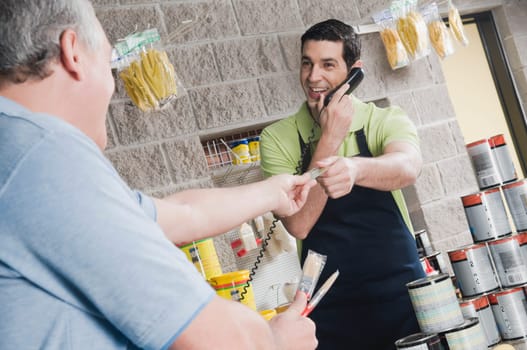 Sales clerk talking on the telephone and giving a credit card to a customer