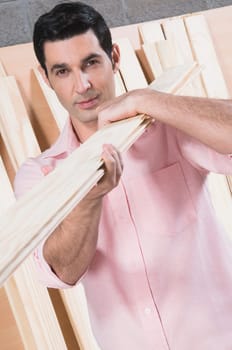 Close-up of a man carrying wooden planks on his shoulder