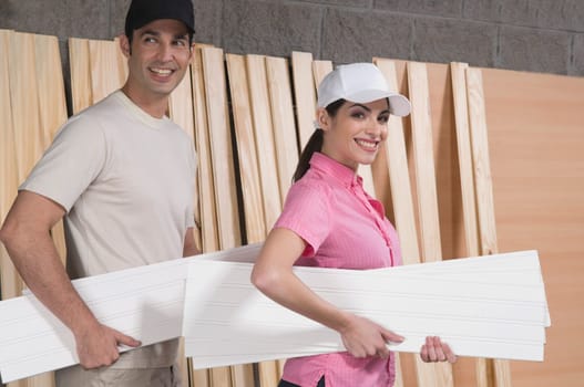 Portrait of a couple holding sheets of plywood
