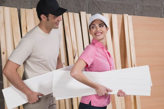 Couple holding sheets of plywood