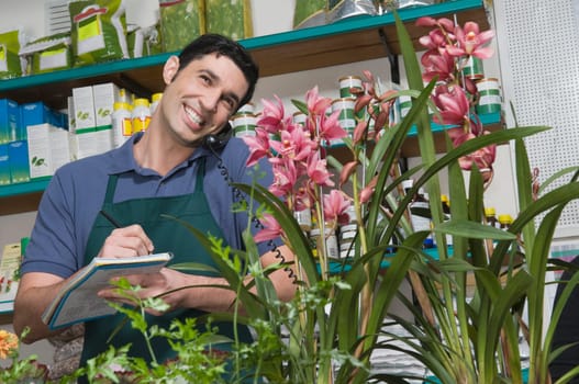 Male sales clerk taking order in a flower shop and smiling