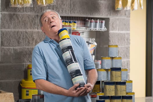 Man holding paint cans and struggling in a hardware store