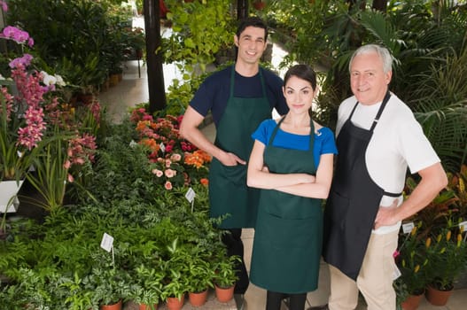 Two men and a woman standing together in a garden center
