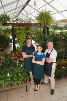 Two men and a woman standing with their arms crossed in a garden center