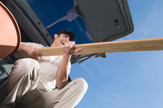 Man holding a wooden plank and laughing
