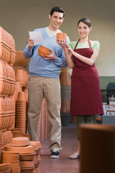 Female sales clerk showing pottery to man in a garden center